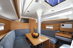 A compact interior with a dining area, seating, a control panel, and a television.