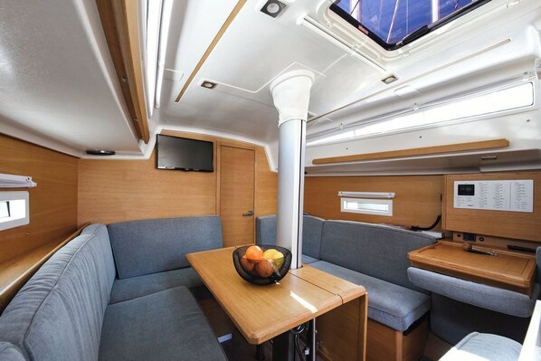 A compact interior with a dining area, seating, a control panel, and a television.