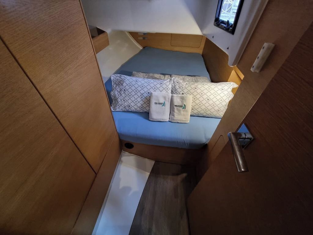 Un interior pequeño y luminoso con una cama, almohadas y un ventanal.