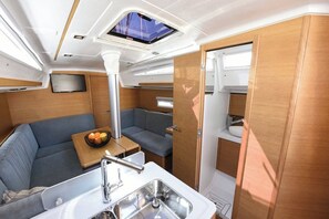 A compact RV interior with a kitchenette, seating area, and a TV. - Sun-Kissed Sailing Adventure in Zadar, Croatia (Zadar)
