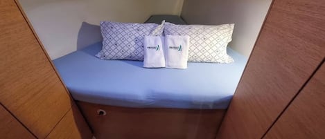 A compact cabin with a bed, pillows, and towels.