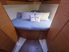 A compact cabin with a bed, pillows, and towels.