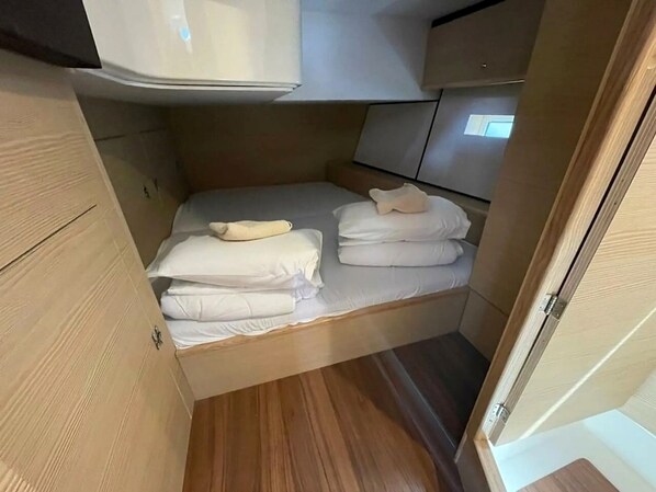 A compact, well-organized sleeping area with a bed, pillows, and a small storage cabinet.