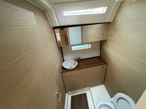 A compact bathroom with a toilet, sink, and a small mirror.