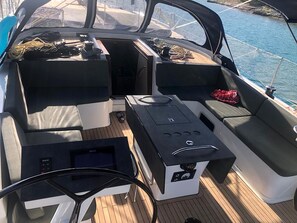A boat's interior with a steering wheel, control panel, and seating area.