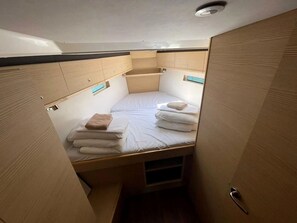 A small, compact bedroom with a single bed, wooden cabinets, and a ceiling light.