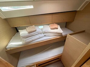 A bunk bed with a skylight above, wooden headboard, and a small compartment below.