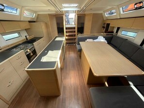 A compact kitchen with a stove, cabinets, and a dining area with a table and benches.