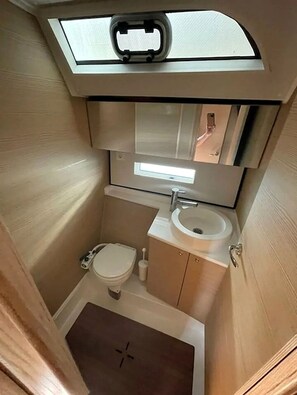 A compact bathroom with a toilet, sink, and mirror.