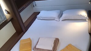 Cama com lençóis brancos, duas almofadas e três toalhas dobradas.