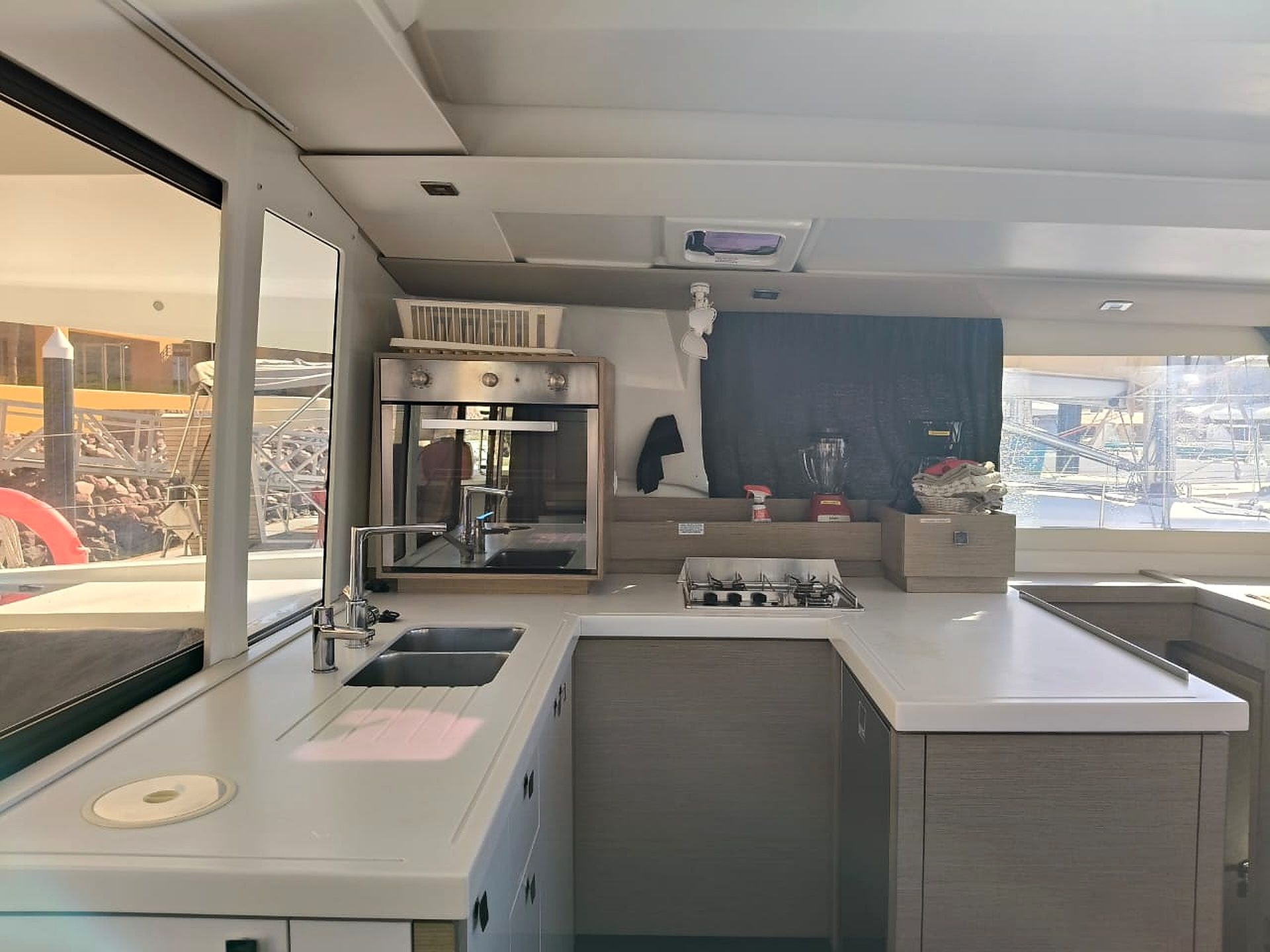 Cozinha moderna com forno embutido, pia e janela com vista para um canteiro de obras.