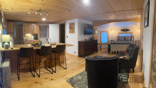 A cozy cabin interior with a kitchen, dining area, and a bedroom with a bed and seating. - Cozy 1-bedroom studio in Historic Stone Village of Chester (Chester)