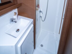 A bathroom with a white sink, a shower, and a wooden vanity.