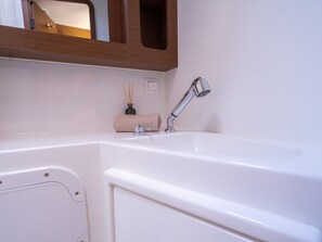 A bathroom with a white sink, a towel, and a bottle of reed sticks.