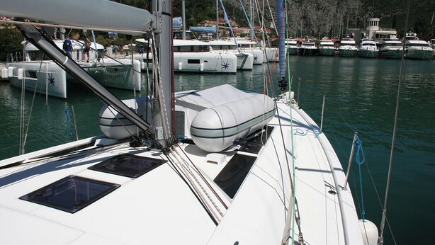 A marina with multiple boats docked, a sailboat with a white hull and a cabin, and a mountainous landscape in the background. - Dubrovnik Delight: A Sun-Kissed Sailing Experience (Komolac)