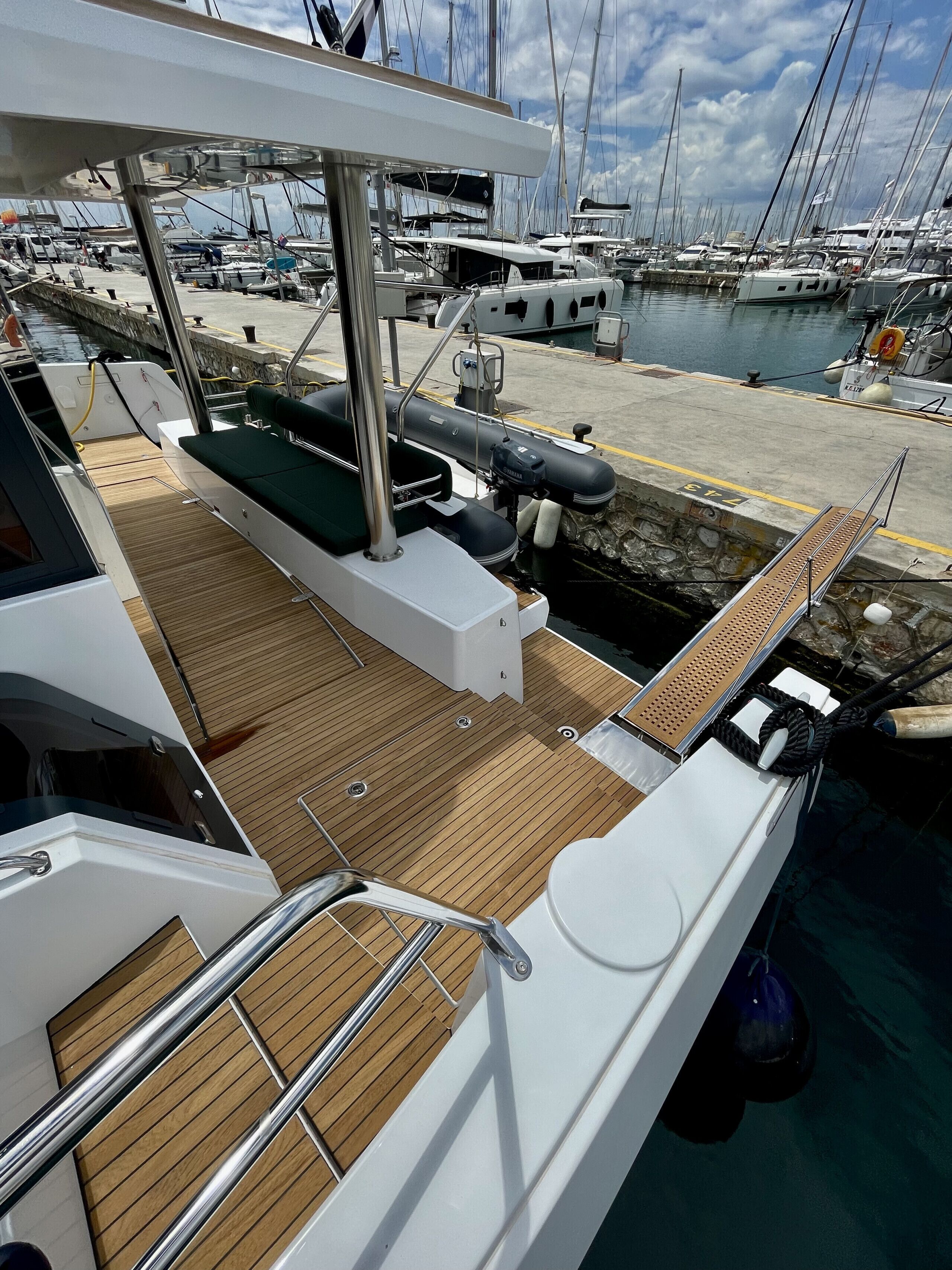 A boat deck with a wooden floor, a green cushioned seat, and a lifebuoy.