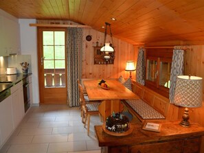 A wooden interior with a dining table, bench seating, a kitchen area, and a window with curtains. - Hornflue (Wohlwender) Appartement/Fewo, Dusche oder Bad, WC 2-Bettwohnung by Interhome (Gstaad)