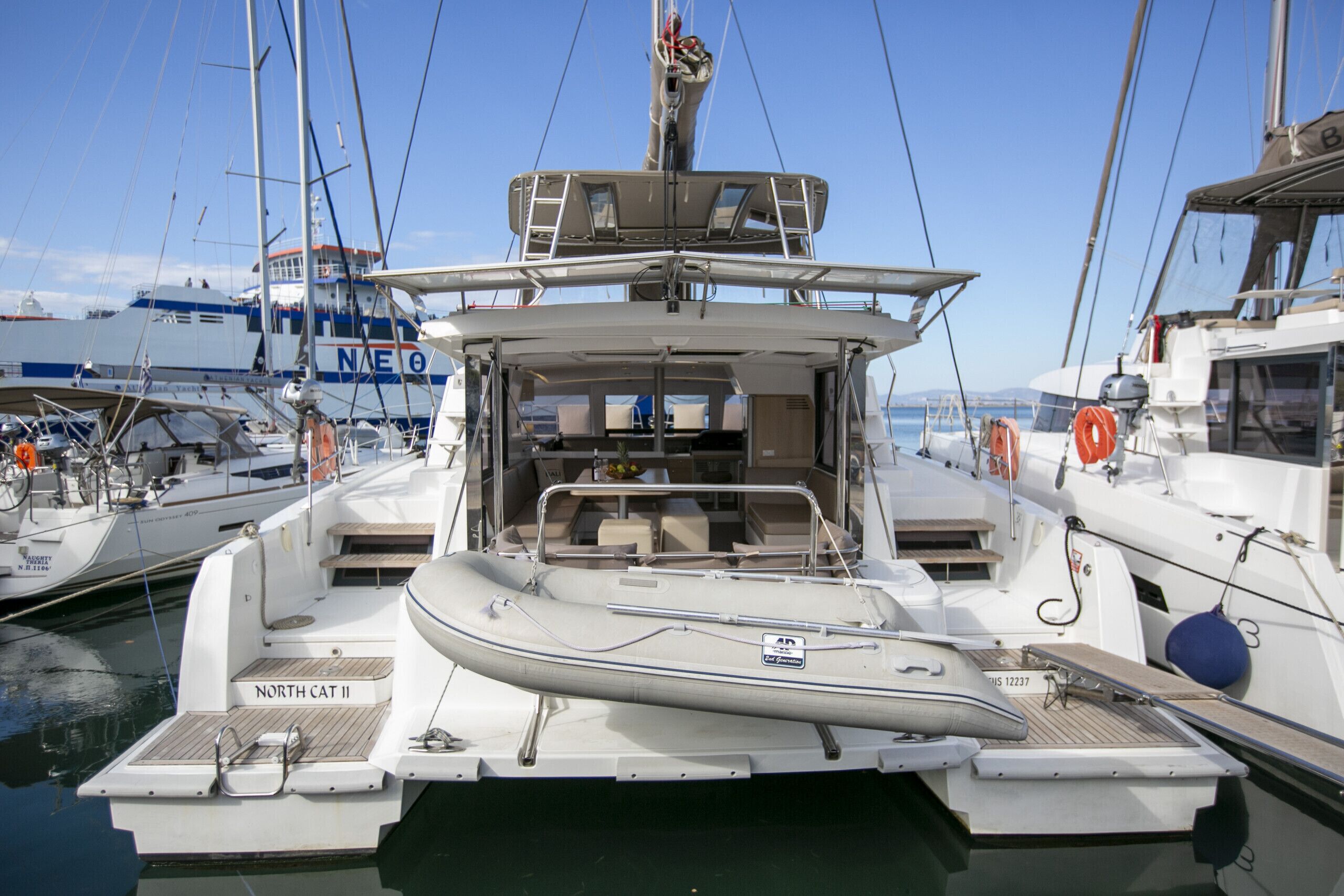 A marina with boats docked, including a white yacht named 'NORTH CAT II' with a covered deck and a small inflatable boat.
