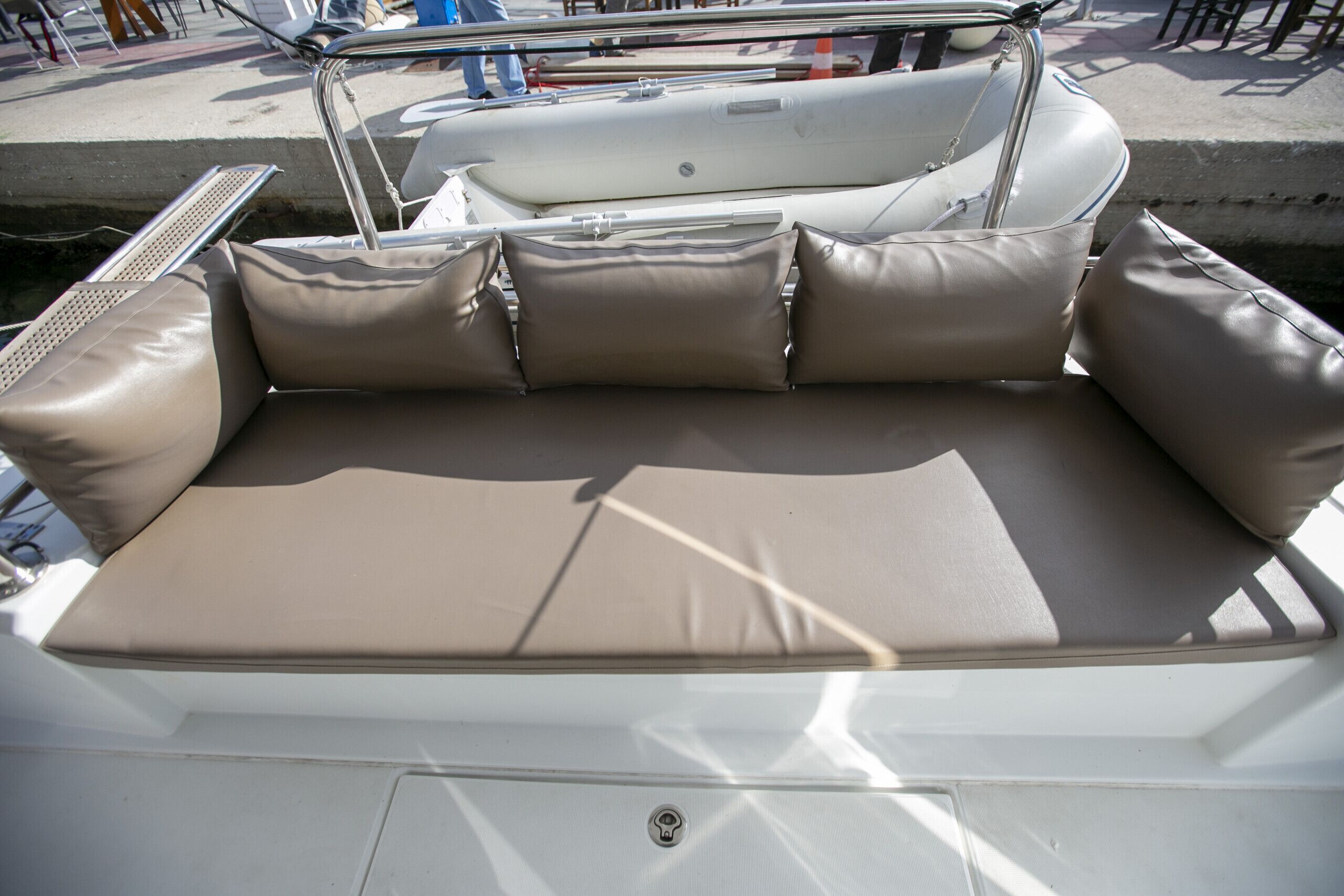 A boat with a cushioned seating area, metal railings, and a white exterior.