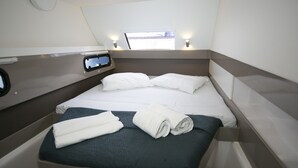 Ein kleines Zimmer mit einem Bett, einem kleinen Fenster und einer Bedienkonsole an der Wand.