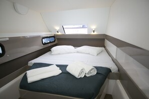 Ein kleines Zimmer mit einem Bett, einem kleinen Fenster und einer Bedienkonsole an der Wand.