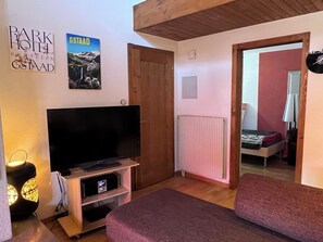 A room with a television, a poster, a door, a radiator, and a bed. - Chez-Nous Appartement/Fewo, Dusche oder Bad, WC 6-Bettwohnung by Interhome (Gstaad)