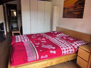 Ein Schlafzimmer mit einem Bett, einem Nachttisch aus Holz, einem Kleiderschrank und einem Bild an der Wand.