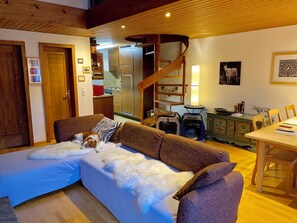 Ein gemütliches Wohnzimmer mit einer Holztreppe, einem Essbereich und einem Bereich, der auch für Haustiere geeignet ist.