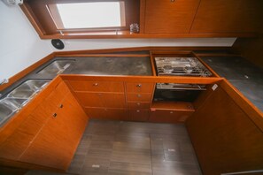 A compact kitchen with wooden cabinetry, a stainless steel sink, and a small window above the countertop. - Sun-kissed Sailing Adventure in Split-Dalmatia, Croatia (Seget Donji)