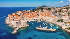 Eine Küstenstadt mit historischer Architektur, einem Hafen voller Boote und einem tiefblauen Meer.