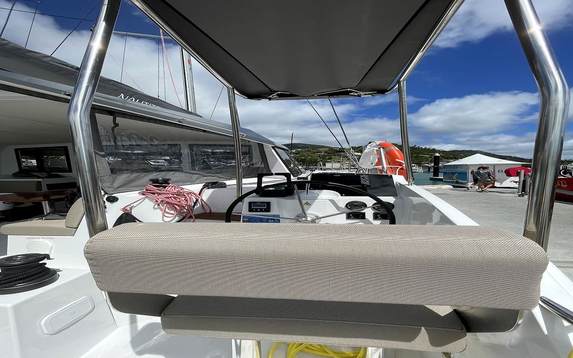 Interior de un barco con timón, panel de control y zona de estar.