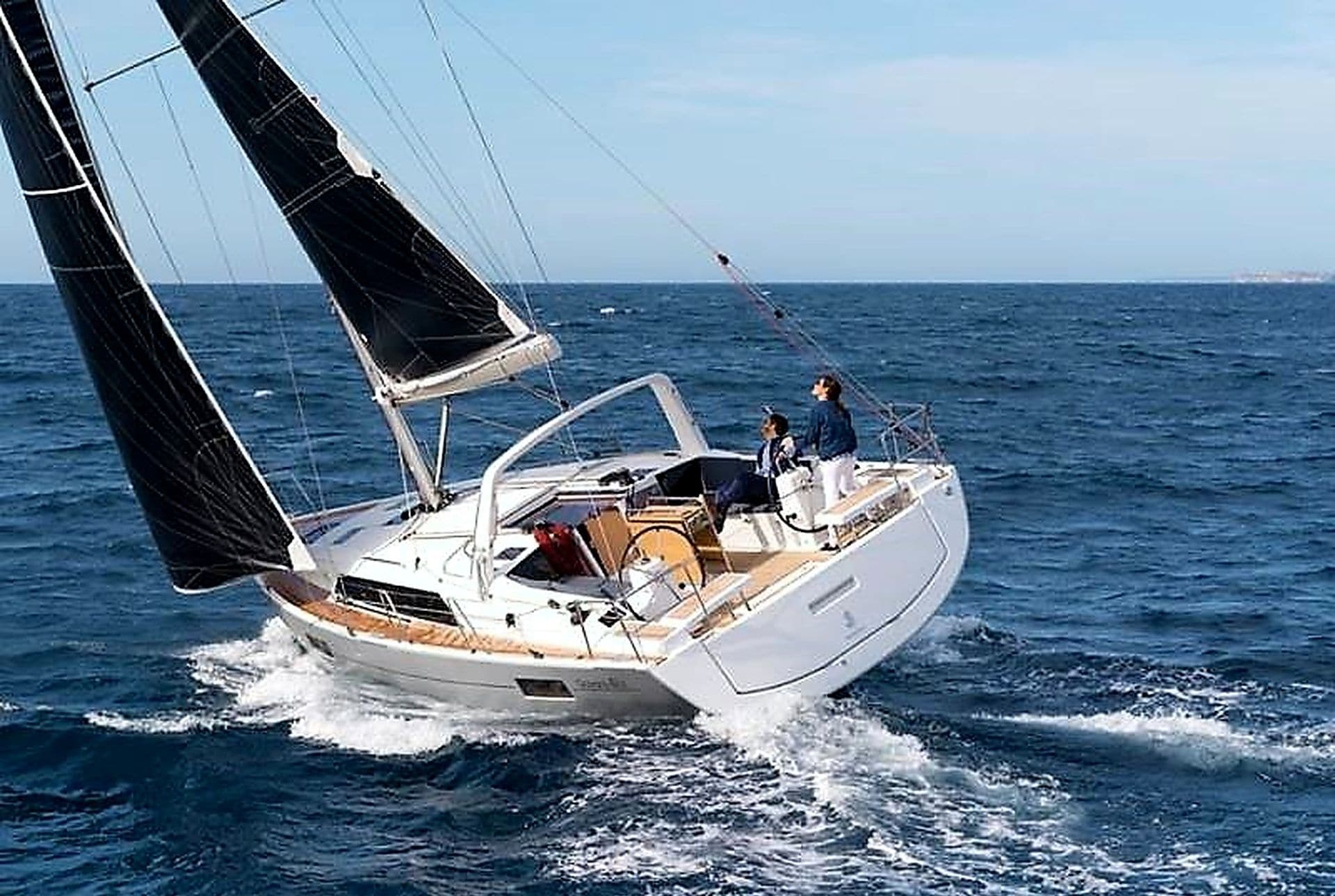 Eine Segelyacht mit Kabine, Deck und zwei Personen an Bord.