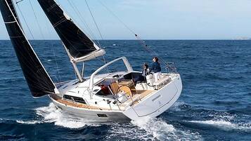 Eine Segelyacht mit Kabine, Deck und zwei Personen an Bord.