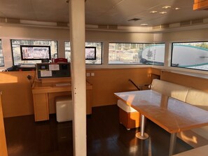 Eine kleine Küche mit einem Kühlschrank, einer Holz Arbeitsplatte und einem Fenster mit Blick auf Boote.