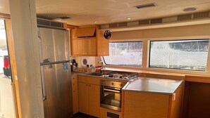 Una cocina compacta con refrigerador, horno y pileta de acero inoxidable.