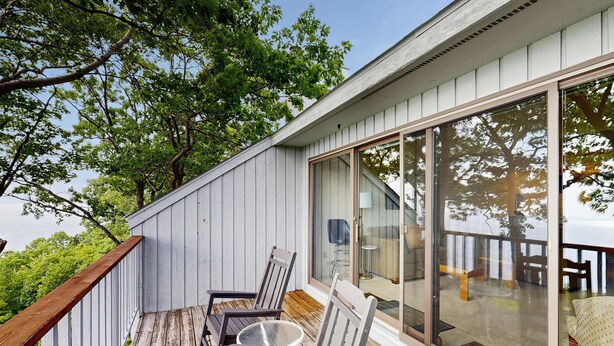 Une terrasse avec des chaises et une table, une porte-fenêtre coulissante et une vue sur l’espace de la terrasse.