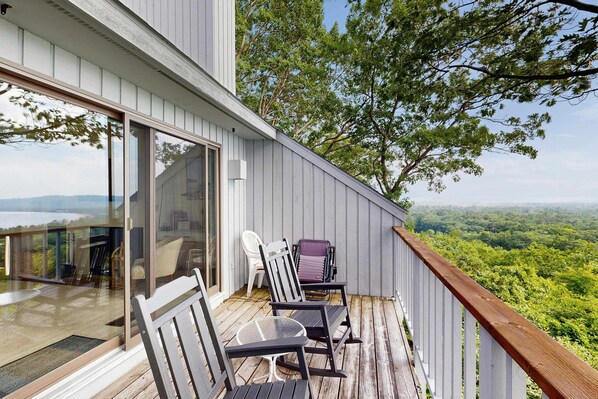 Ein Balkon mit Glastür, zwei Schaukelstühlen und einem Tisch.