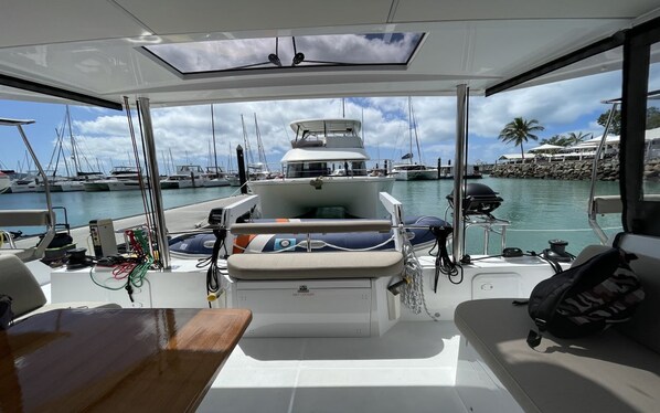 A boat deck with a seating area, a table, and a view of the marina.