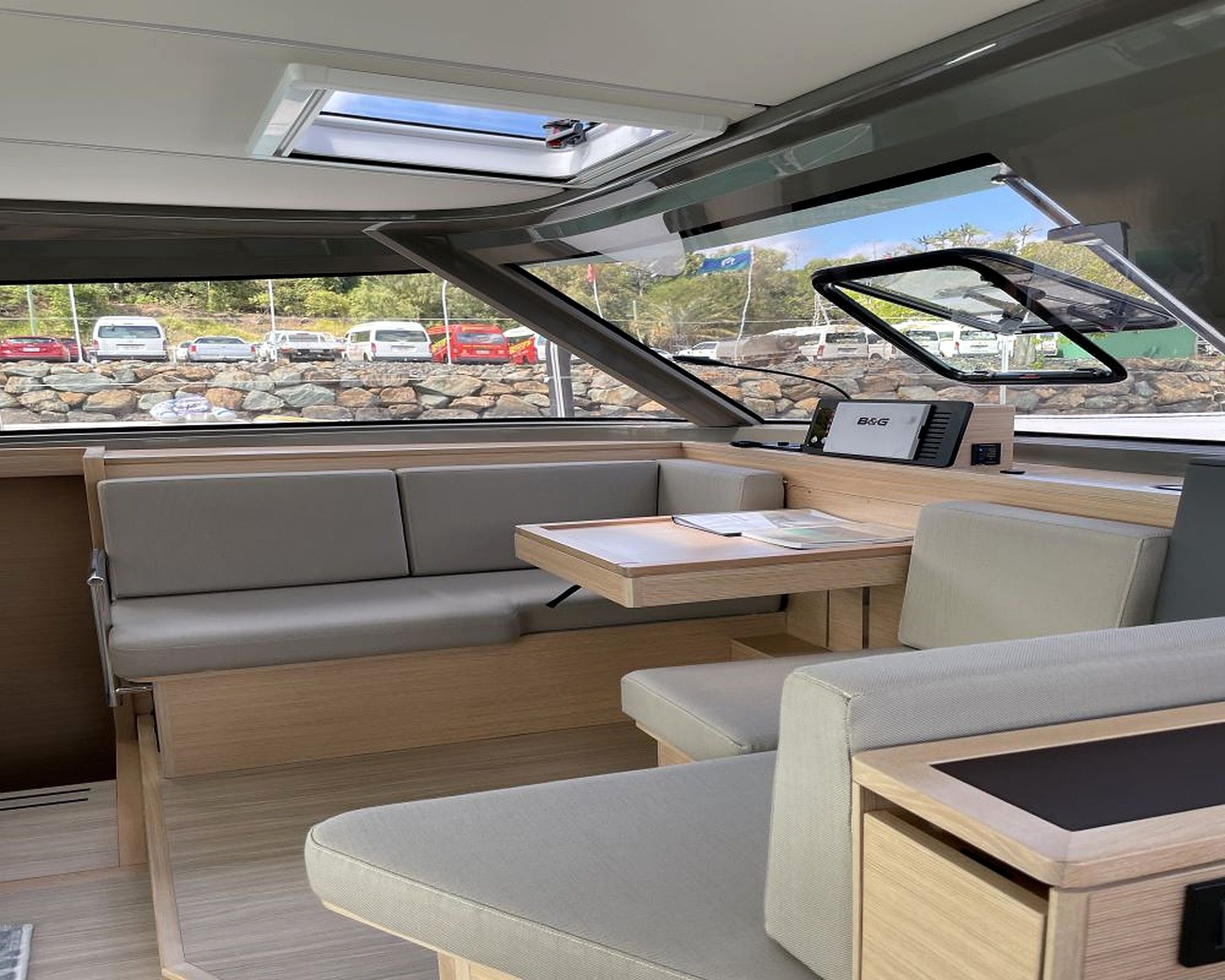 Interior de barco con comedor, asientos acolchados y vistas al exterior.