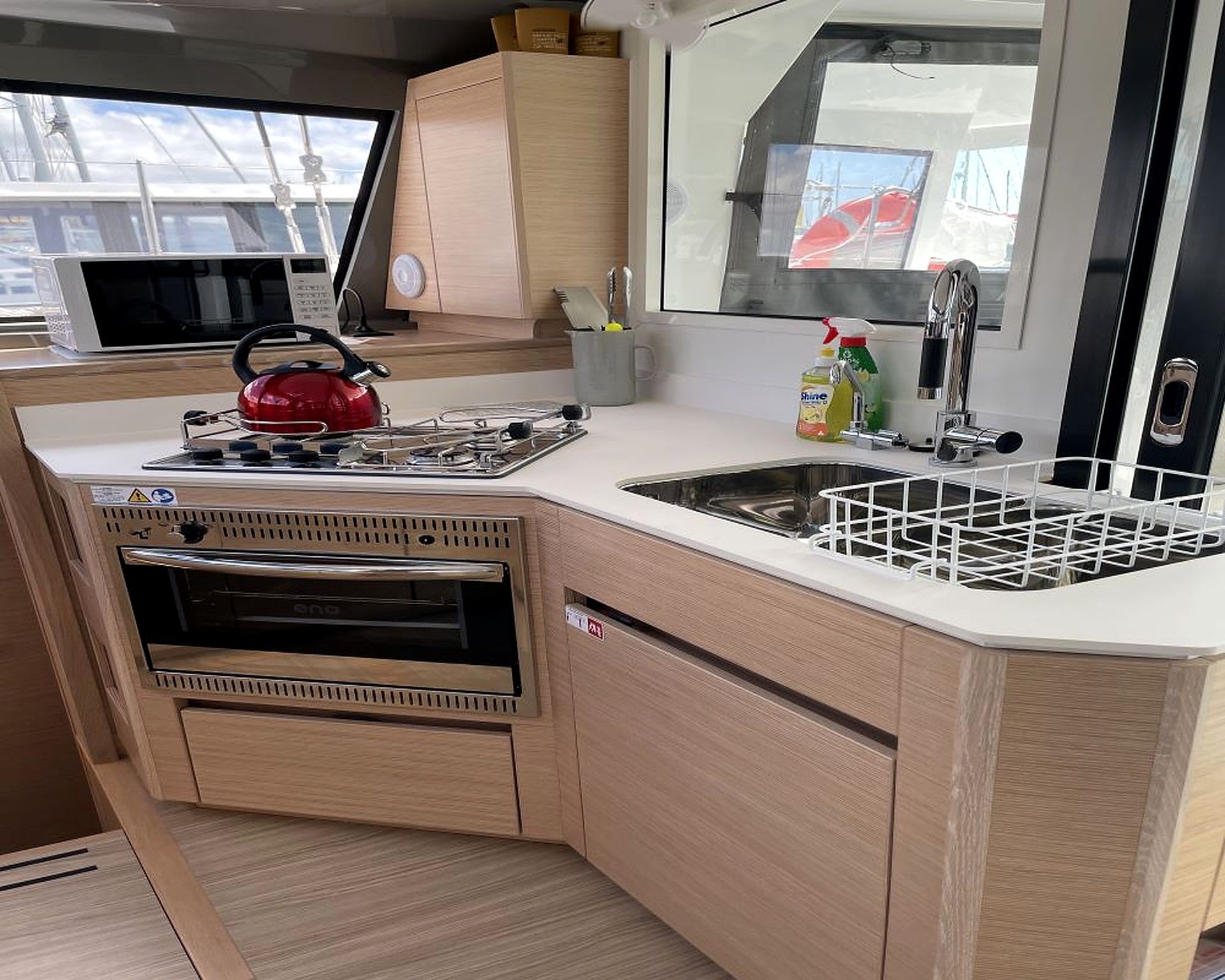 A compact kitchen with a microwave, kettle, sink, and storage cabinets.