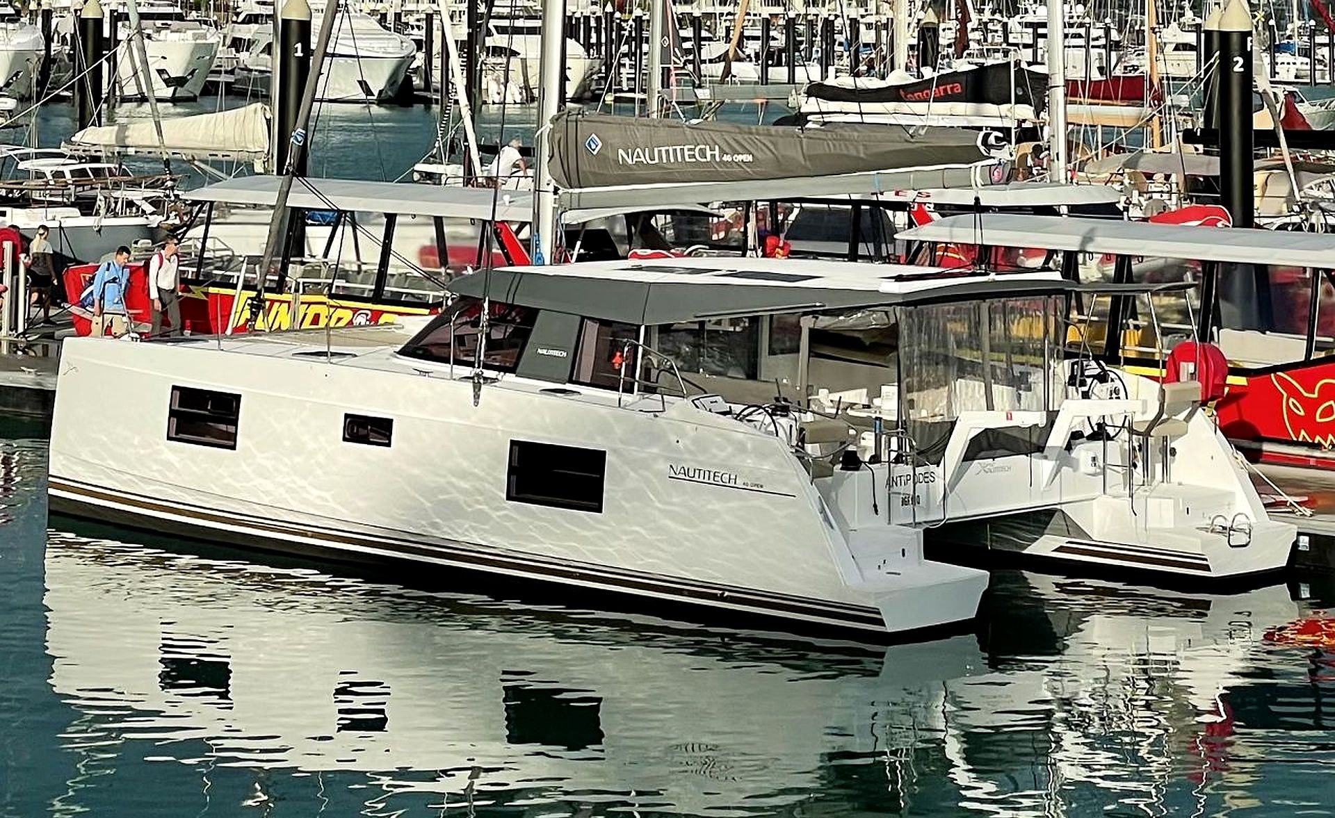A marina with a white yacht docked at a pier, surrounded by other boats.