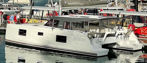 A marina with a white yacht docked at a pier, surrounded by other boats.