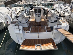 A boat deck with a central seating area, two steering wheels, and a wooden floor. - Sun-Kissed Sailing Adventure in the Ionian Islands, Lefkada (Lefkada)