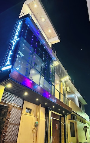A modern building with a glass facade, a prominent 'VEDAS' sign, and a well-lit entrance. - Hotel Vedas Villa 15 mnt frm Ram Temple  (Ayodhya)