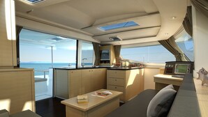 A compact galley with a small kitchenette, a dining area, and a seating space with a view of the sea.