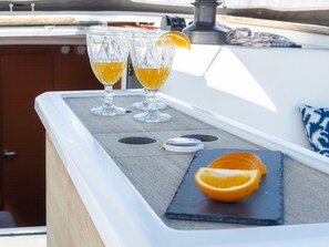 A bar area with two glasses of amber liquid, a coaster, and a half orange on a slate board. - Sun-Kissed Sailing Adventure in Istria, Croatia (Pula)