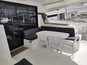 A yacht interior with a seating area, a table, and a view of other yachts through a glass door. - Caribbean Dream: Sun-Kissed Sailing Adventure from Guadalupe, Grande-Terre (Pointe-à-Pitre)