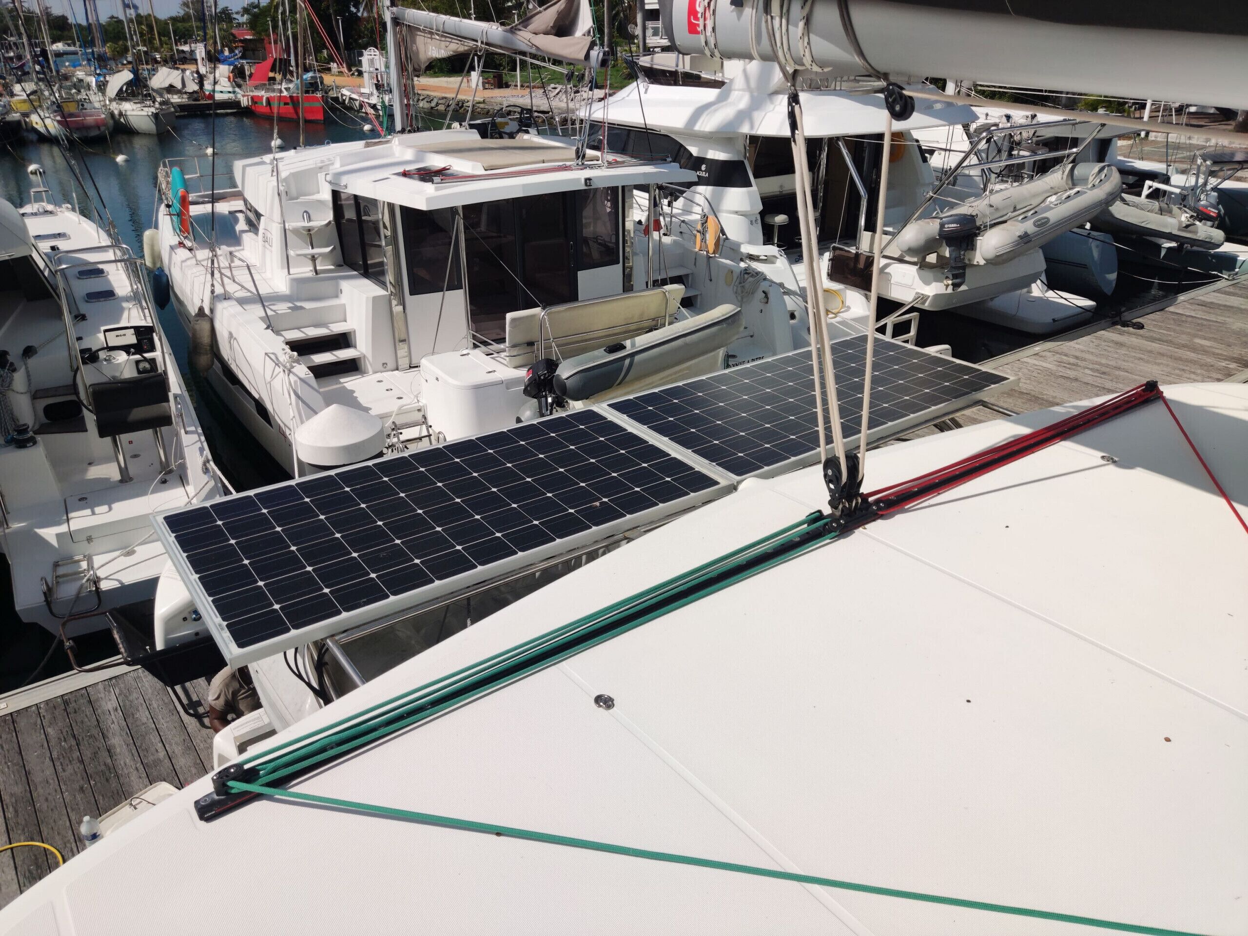 Un puerto deportivo con barcos amarrados, paneles solares en la cubierta y un barco blanco con cabina.