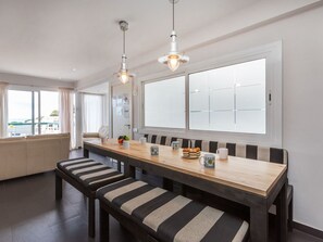 A modern dining area with a wooden table, striped benches, and pendant lighting. - Punta Aromir by Interhome (Tossa de Mar)