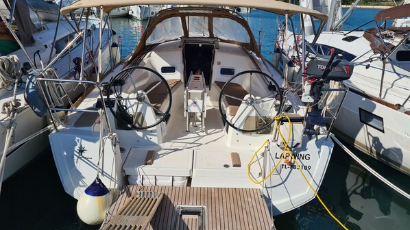 Ein Bootsdeck mit Steuerrad, kleinem Tisch und Rettungsboje.